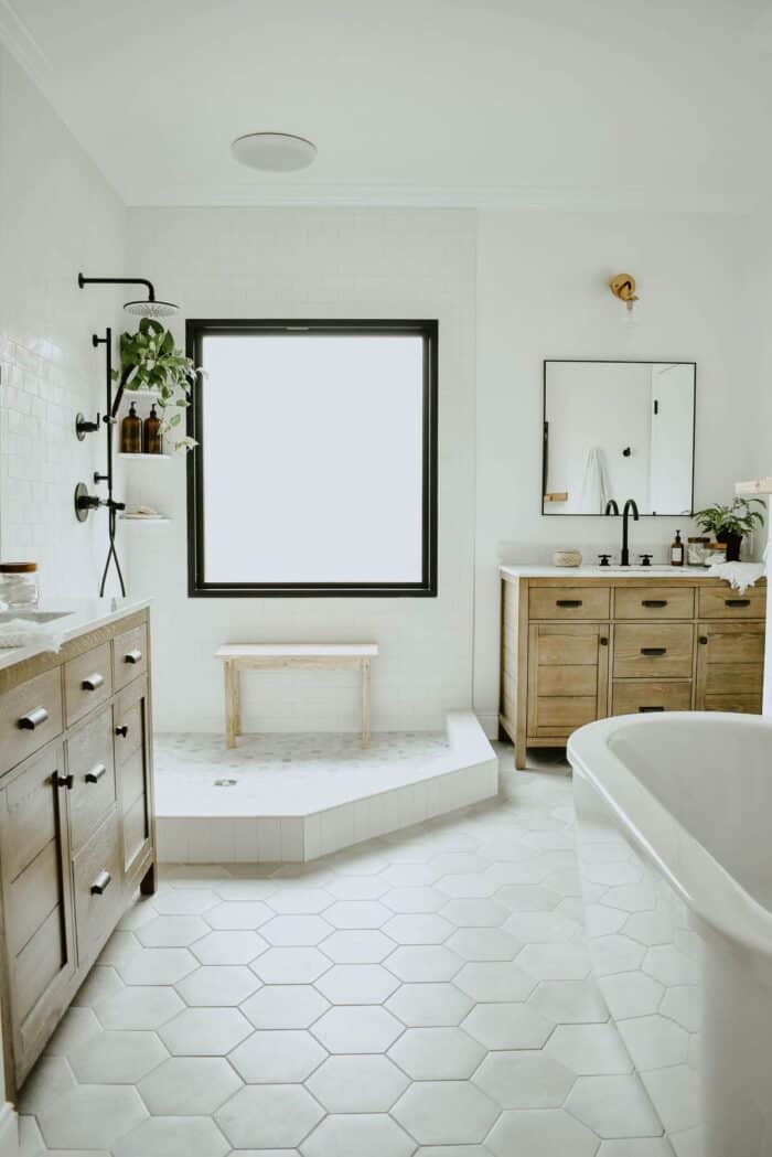 A white bathroom with a modern tub and hexagon tile floor.