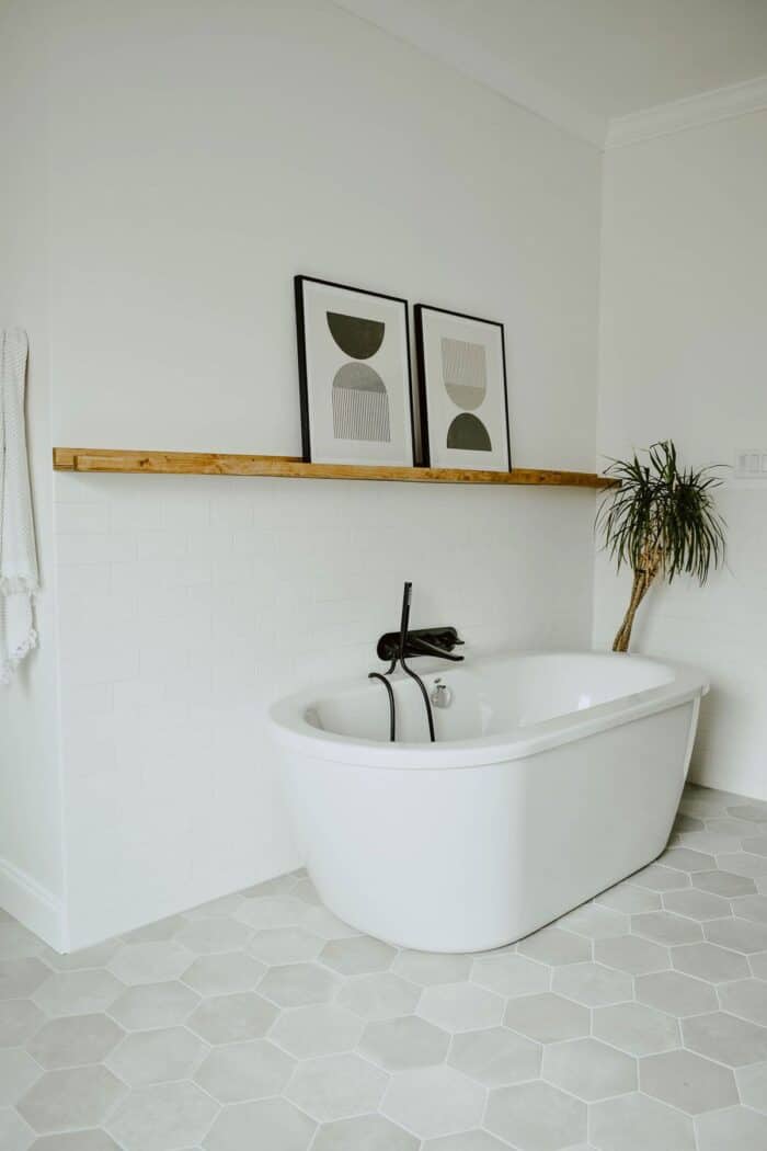 A white bathroom with a modern tub and hexagon tile floor.