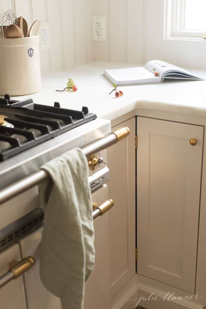 Cream kitchen cabinets topped with a marble eased edge countertop.