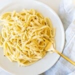 pasta tossed with lemon pepper sauce on white plate with gold fork