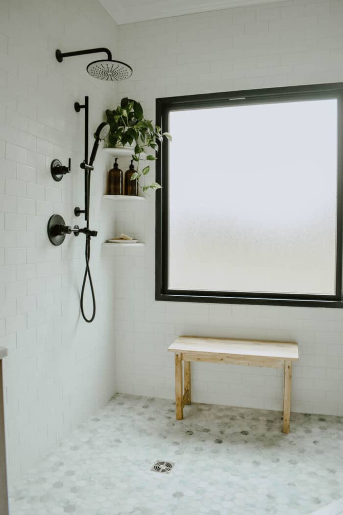 A white bathroom with a modern tub and hexagon tile floor.