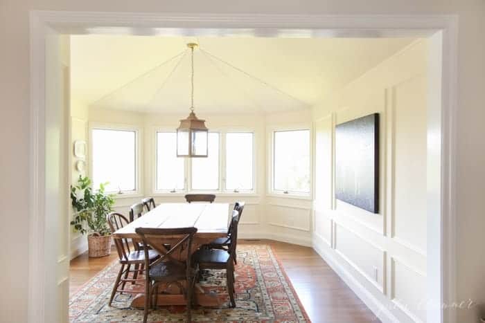 A white dining room with a brass lantern and box molding on the walls.