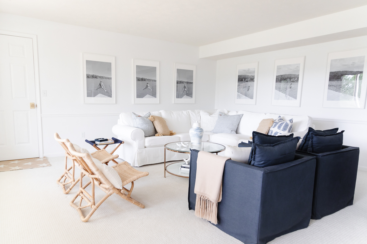A white living room with a wall of windows, two navy blue chairs and a white sectional sofa.
