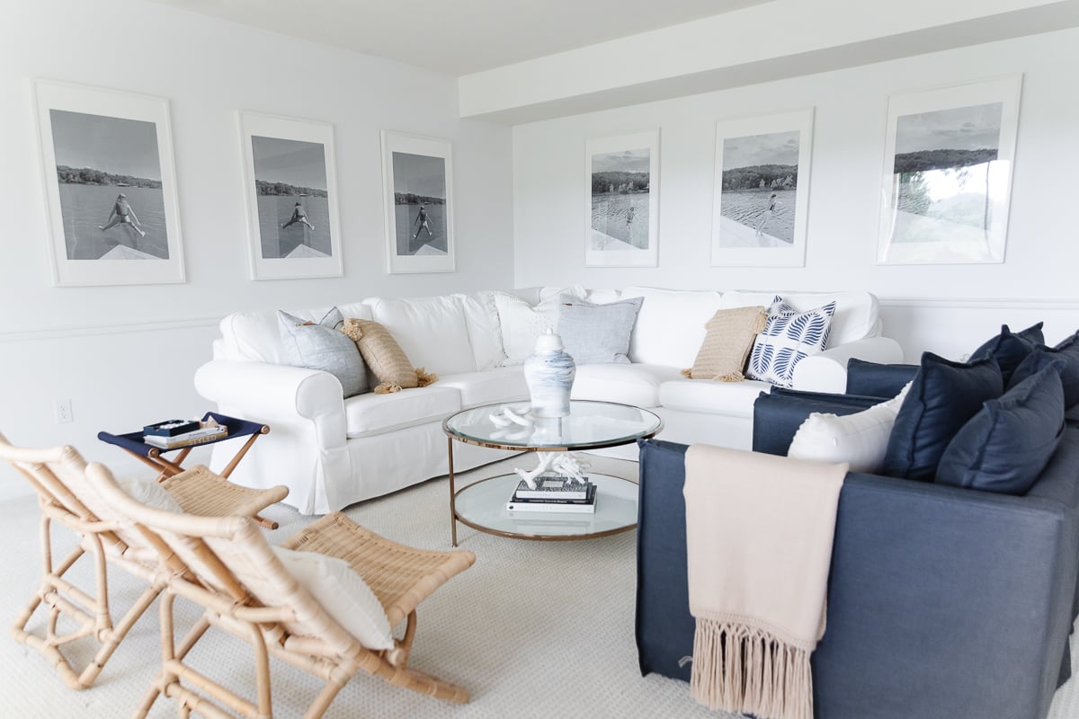 A white living room with a wall of windows, two navy blue chairs and a white sectional sofa.