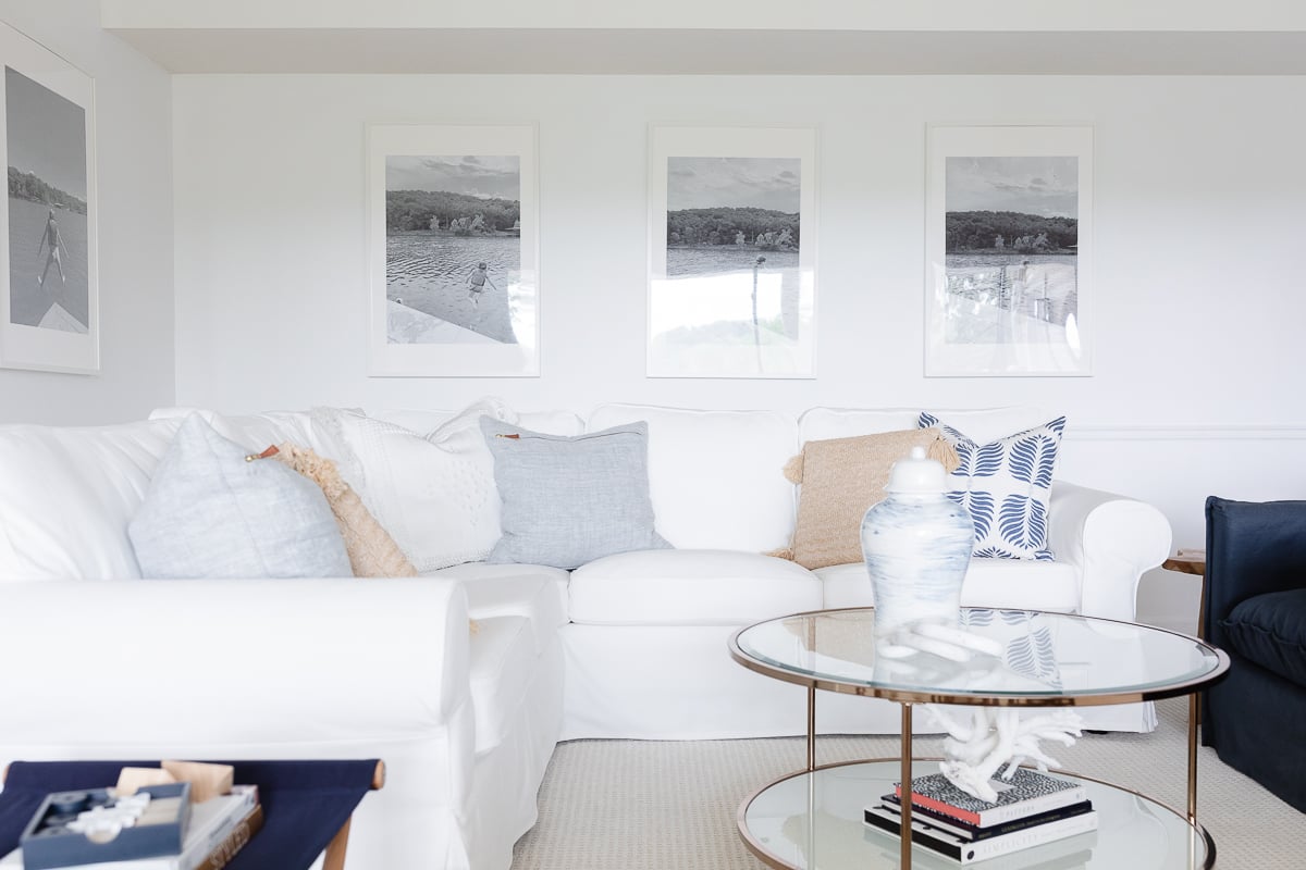 A white living room with a wall of windows, two navy blue chairs and a white sectional sofa. 