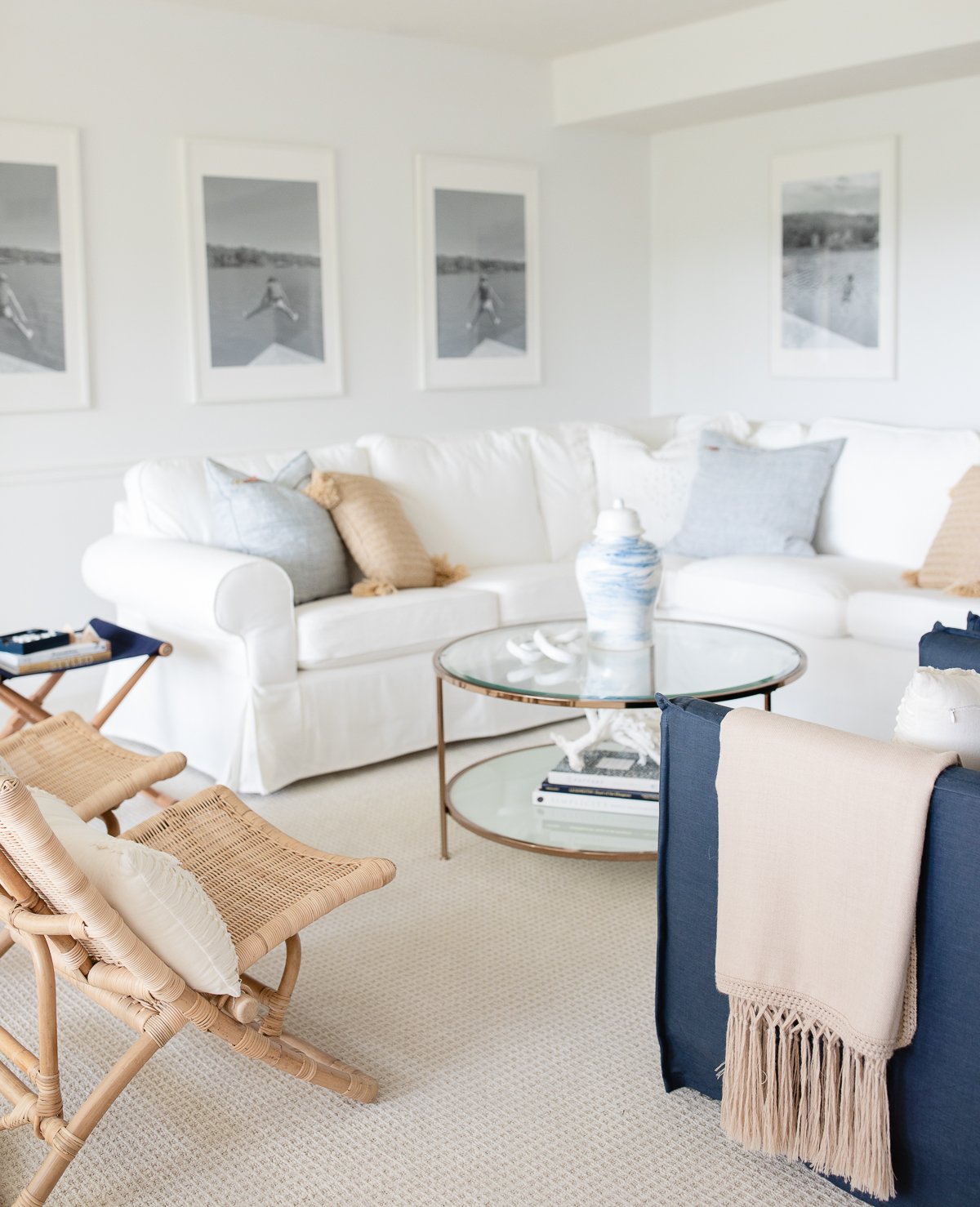 A white living room with a wall of windows, two navy blue chairs and a white sectional sofa.