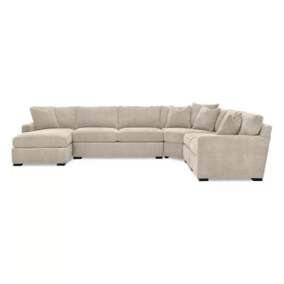 A soft beige colored sectional sofa against a white background.