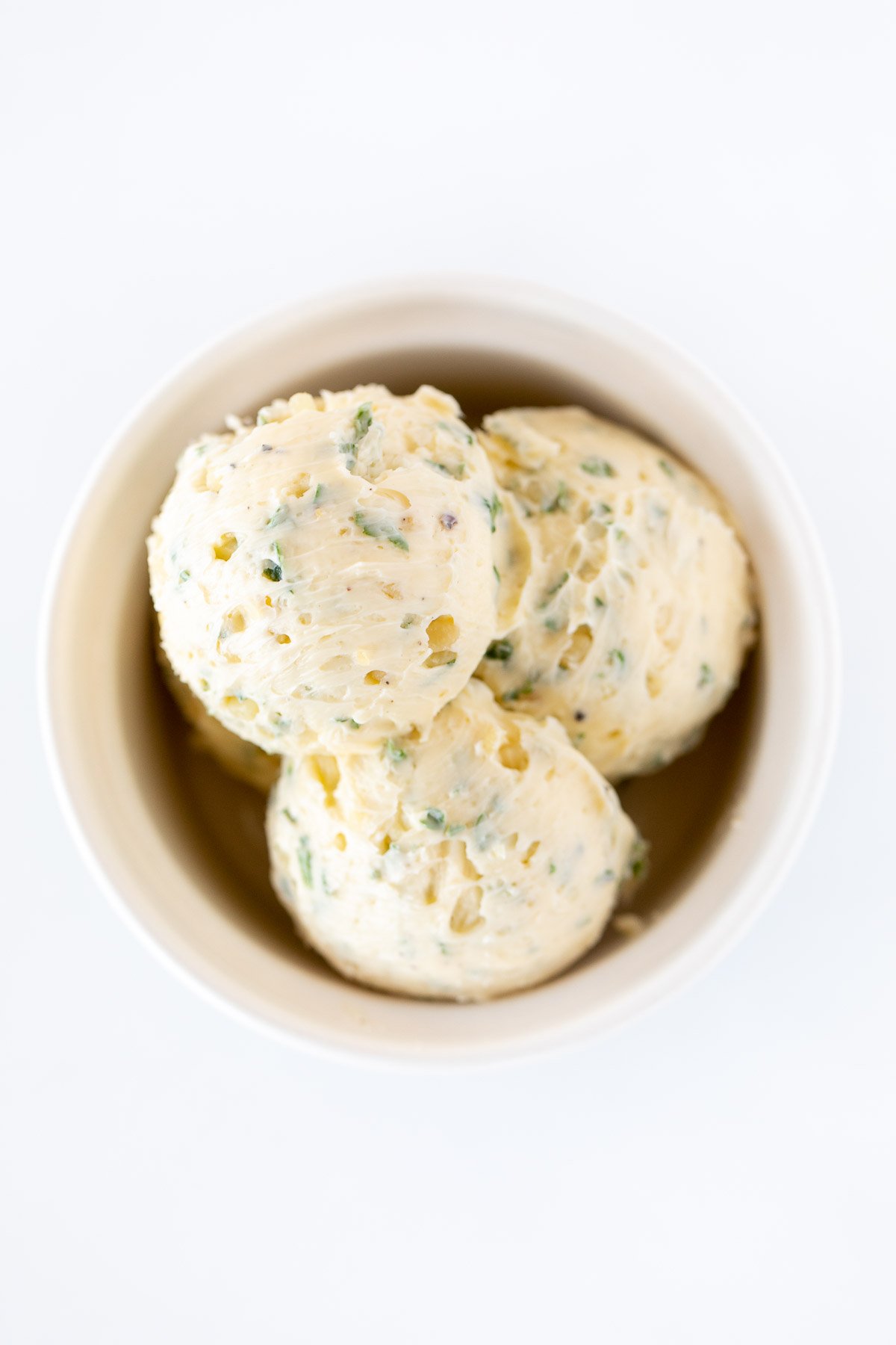 Scoops of herbed steak butter inside a white bowl.