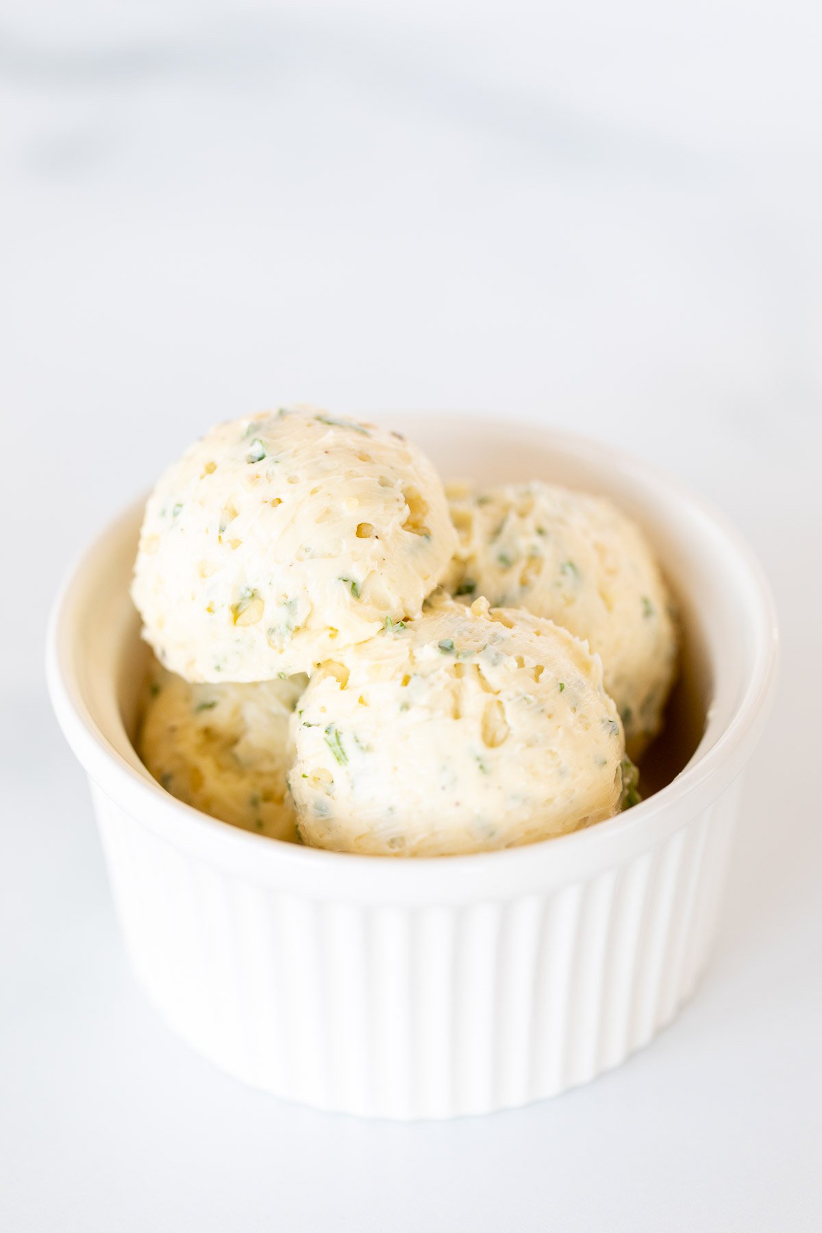 Scoops of herbed steak butter inside a white bowl.
