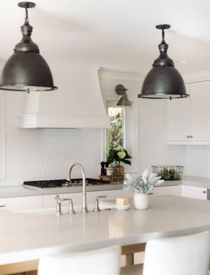 A kitchen with white hexagon tile backsplash and white cabinets.