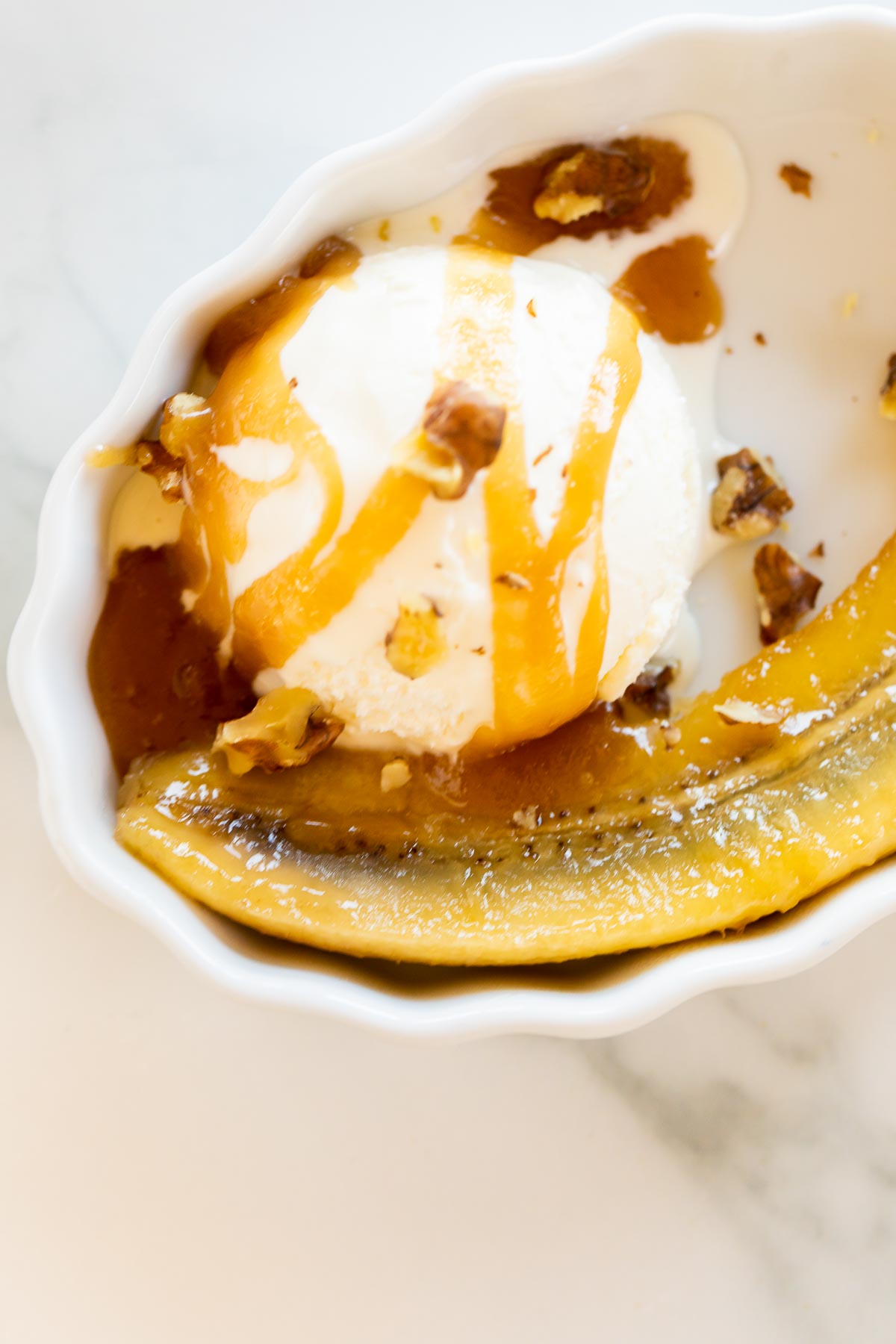 A bowl of ice cream with a banana and caramel sauce, inspired by the classic bananas foster recipe.