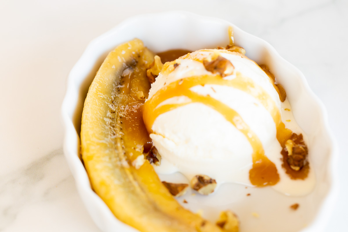 A bowl of ice cream adorned with sweet bananas and drizzled with luscious caramel sauce.