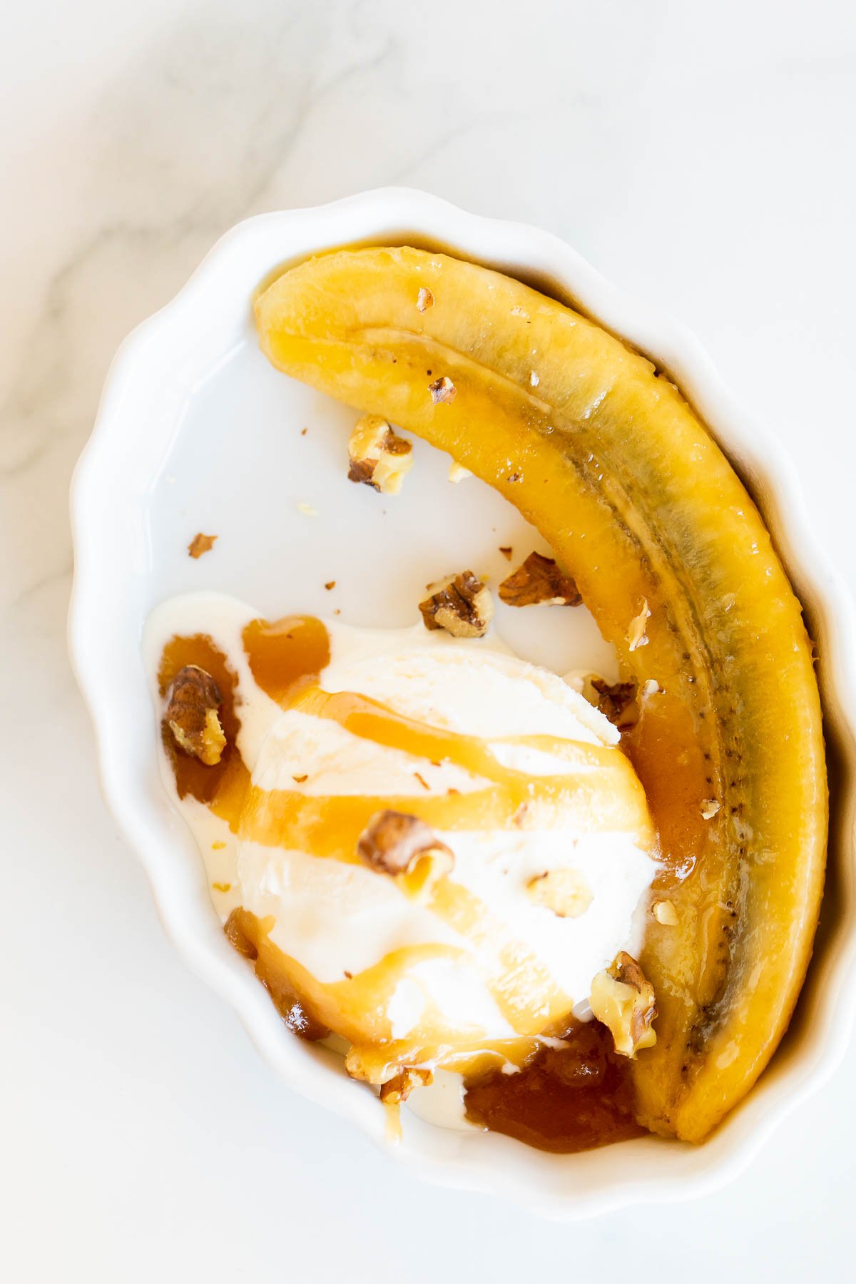 A bowl of ice cream topped with a luscious banana foster sauce.