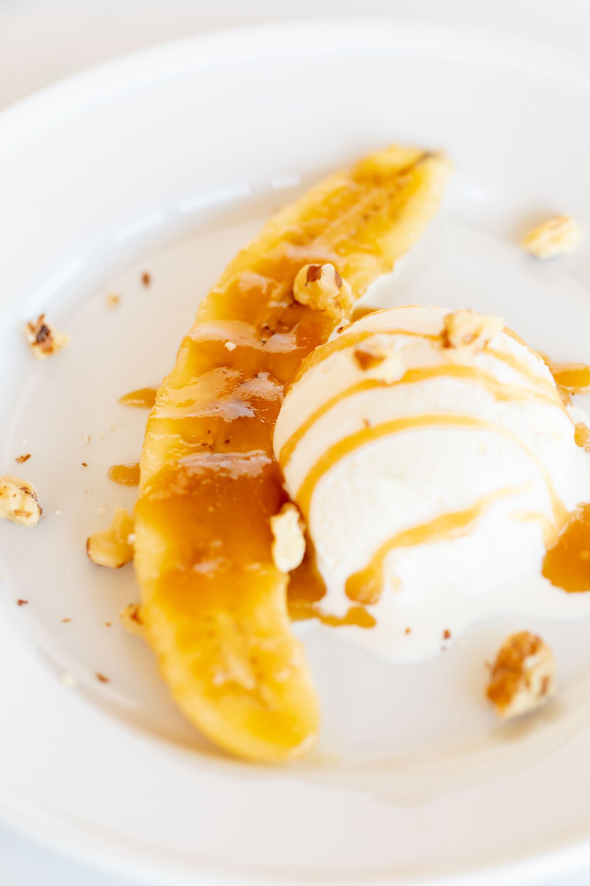 A delicious white plate adorned with ice cream topped off by a tantalizing banana slice.