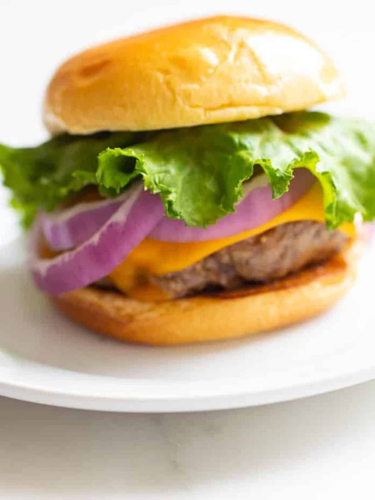 Best Juicy Burger on a white plate in a recipe round up of what to serve with burgers.