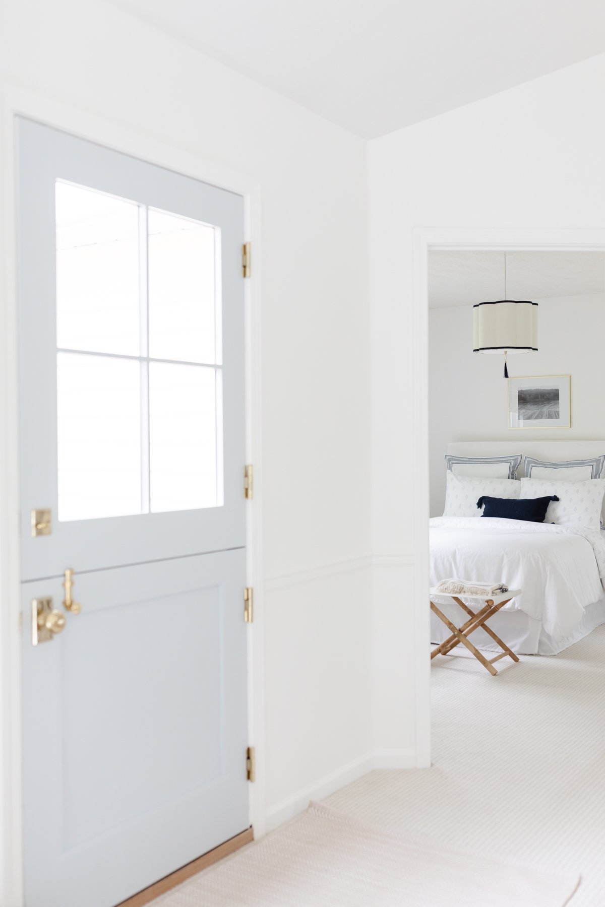 A light and airy bedroom viewed through an open door with a frosted glass pane showcases the best paint for trim, enhancing its aesthetic appeal.