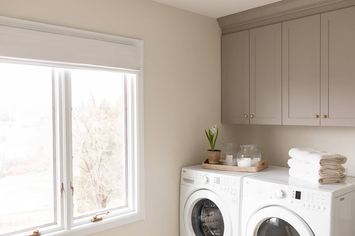 laundry room with roman shade and grey cabinets