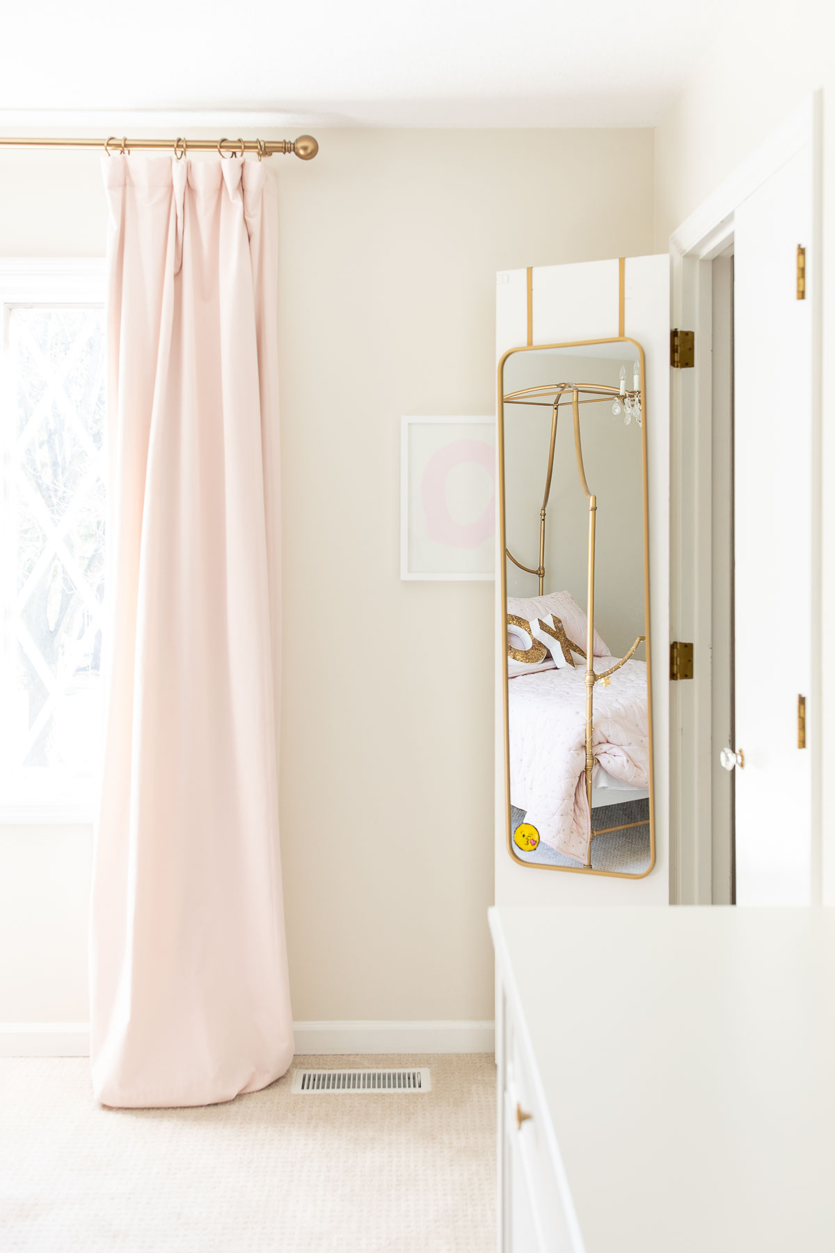 A pink tween bedroom with a gold mirror inside the closet door
