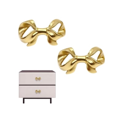Two gold bows on a white dresser in a coquette bedroom.