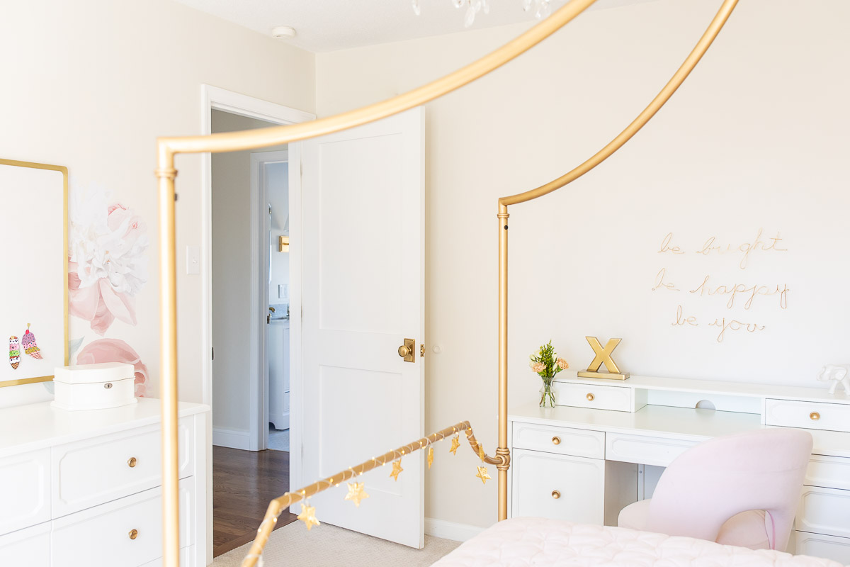 A tween girl bedroom with a gold bed and a white desk, blush pink bedding