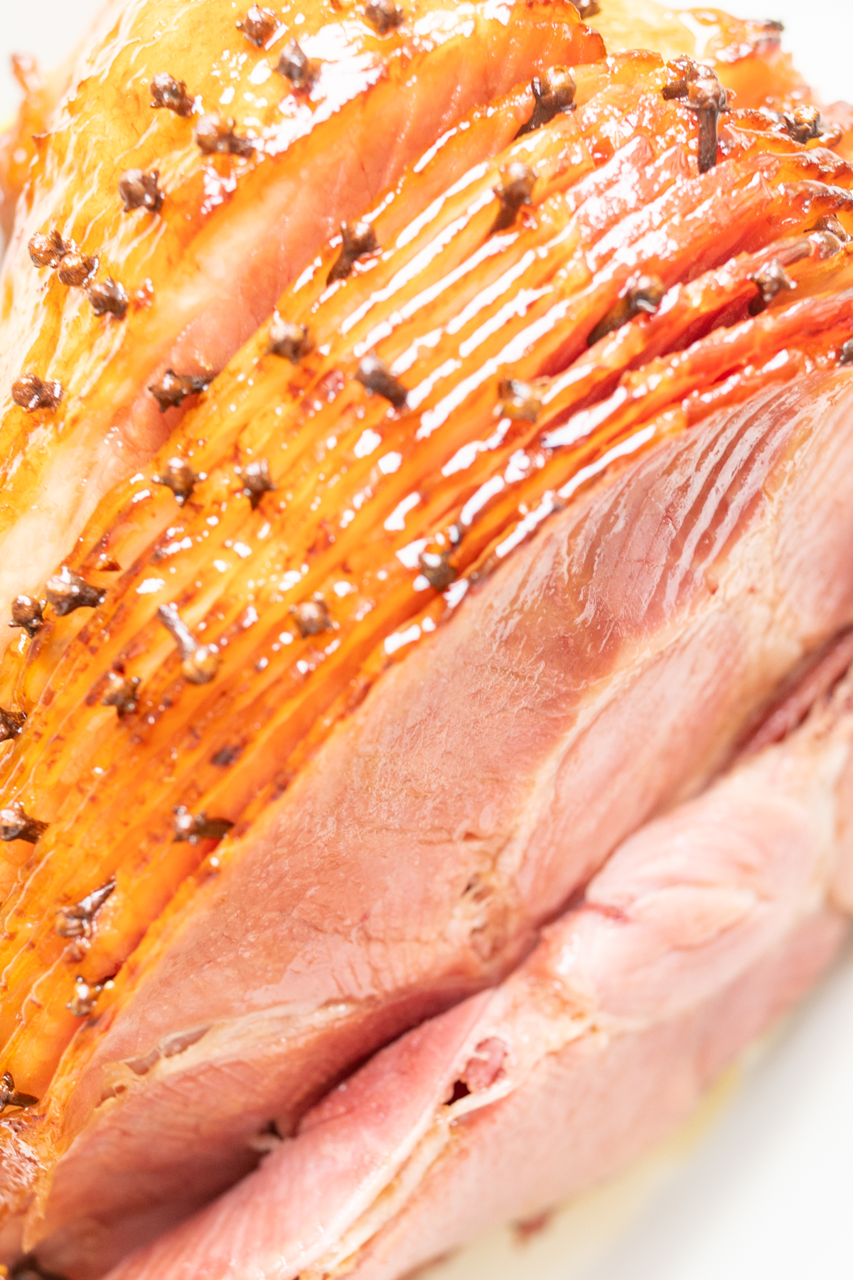 A sliced honey glazed ham studded with cloves.
