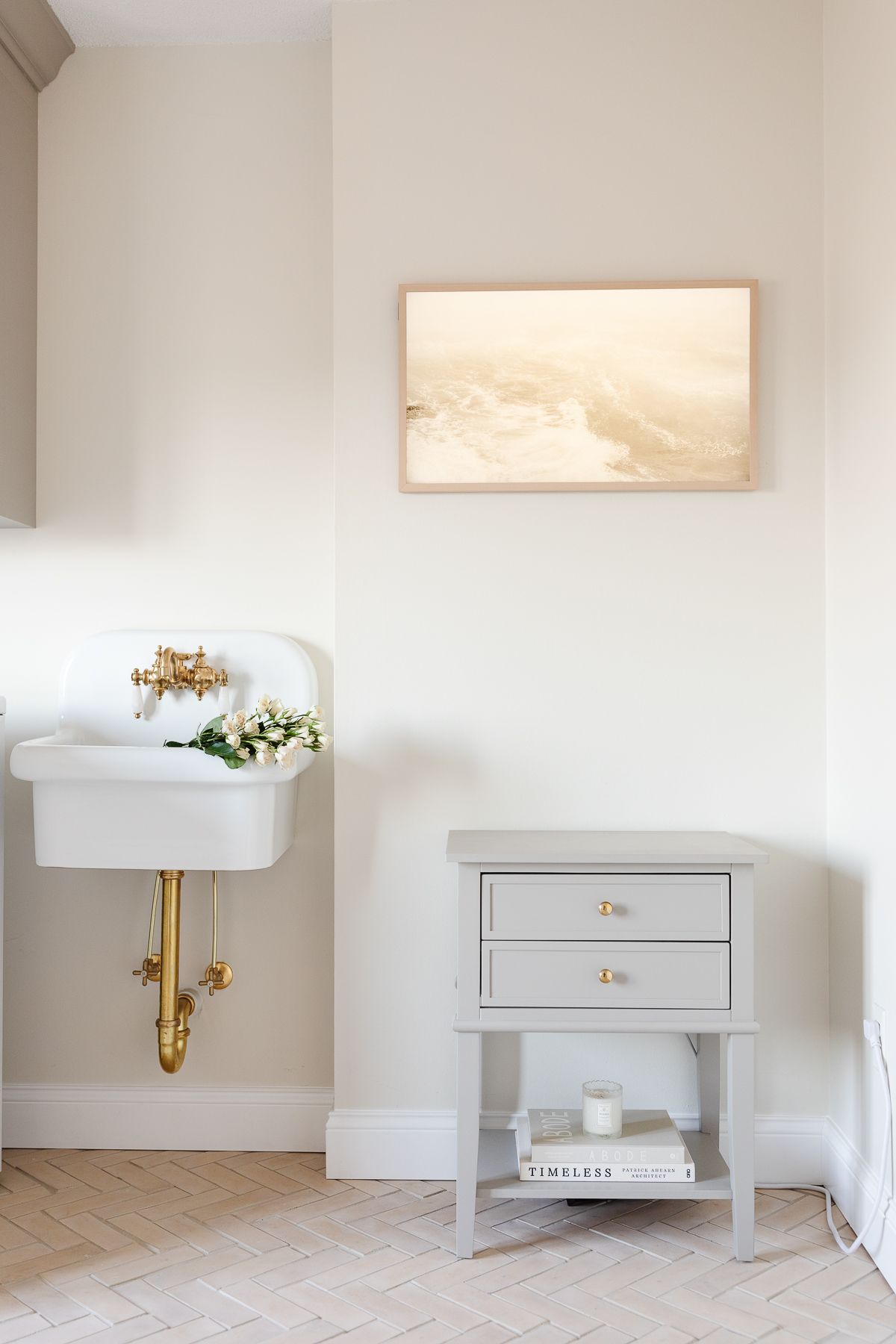 A small wall sink and side table in a laundry room, with a Frame TV above