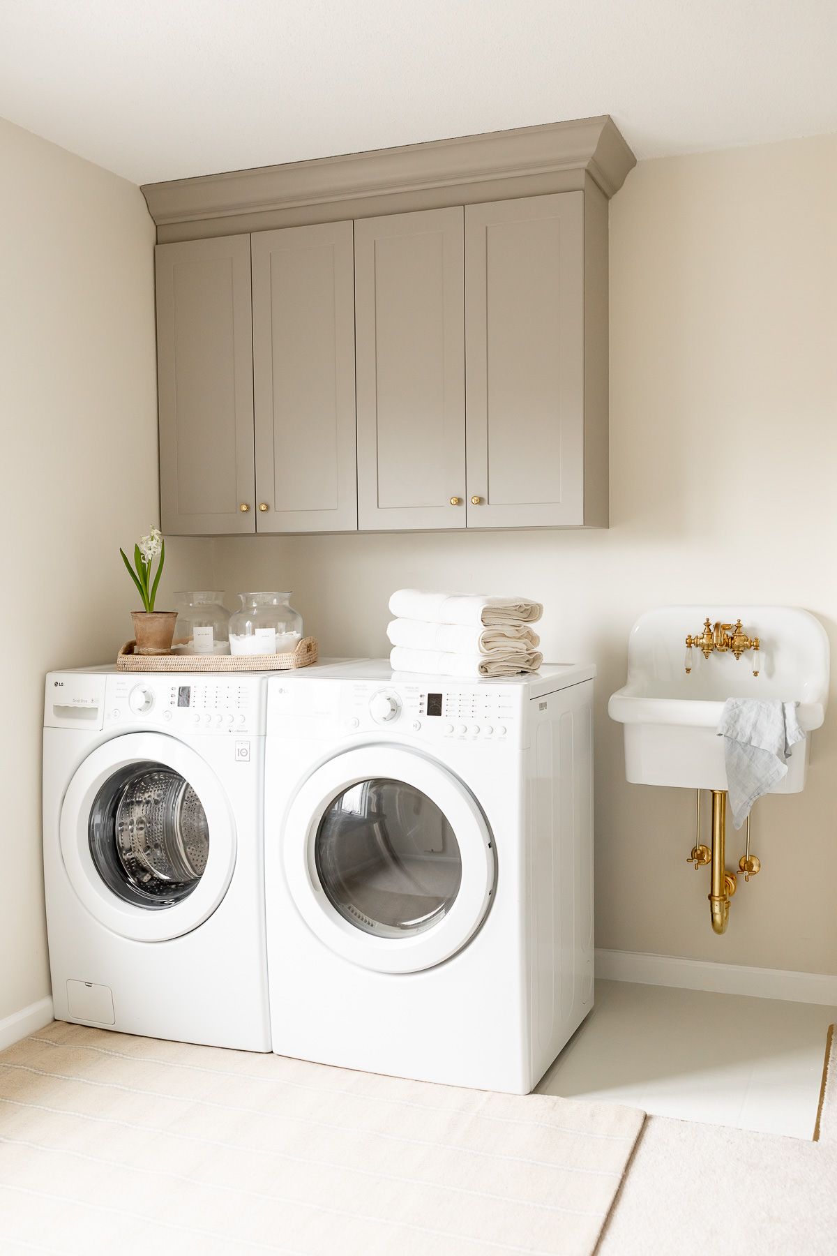 a laundry room with greige cabinetry and a wall sink