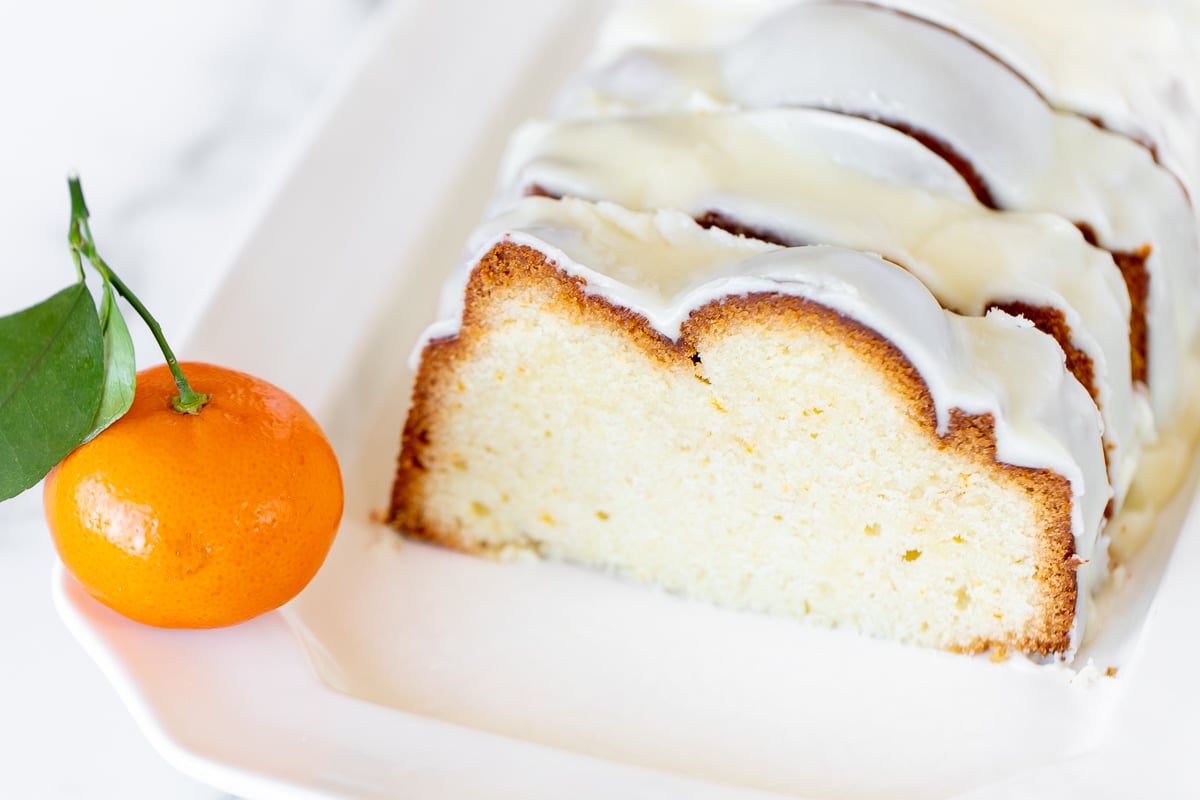 An orange pound cake on a white serving platter.