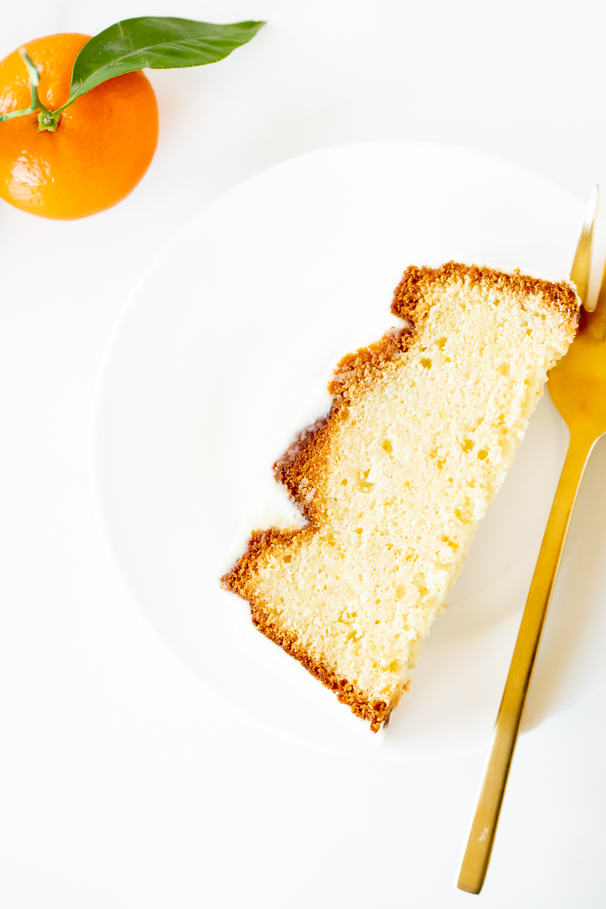 A slice of orange pound cake on a white plate.