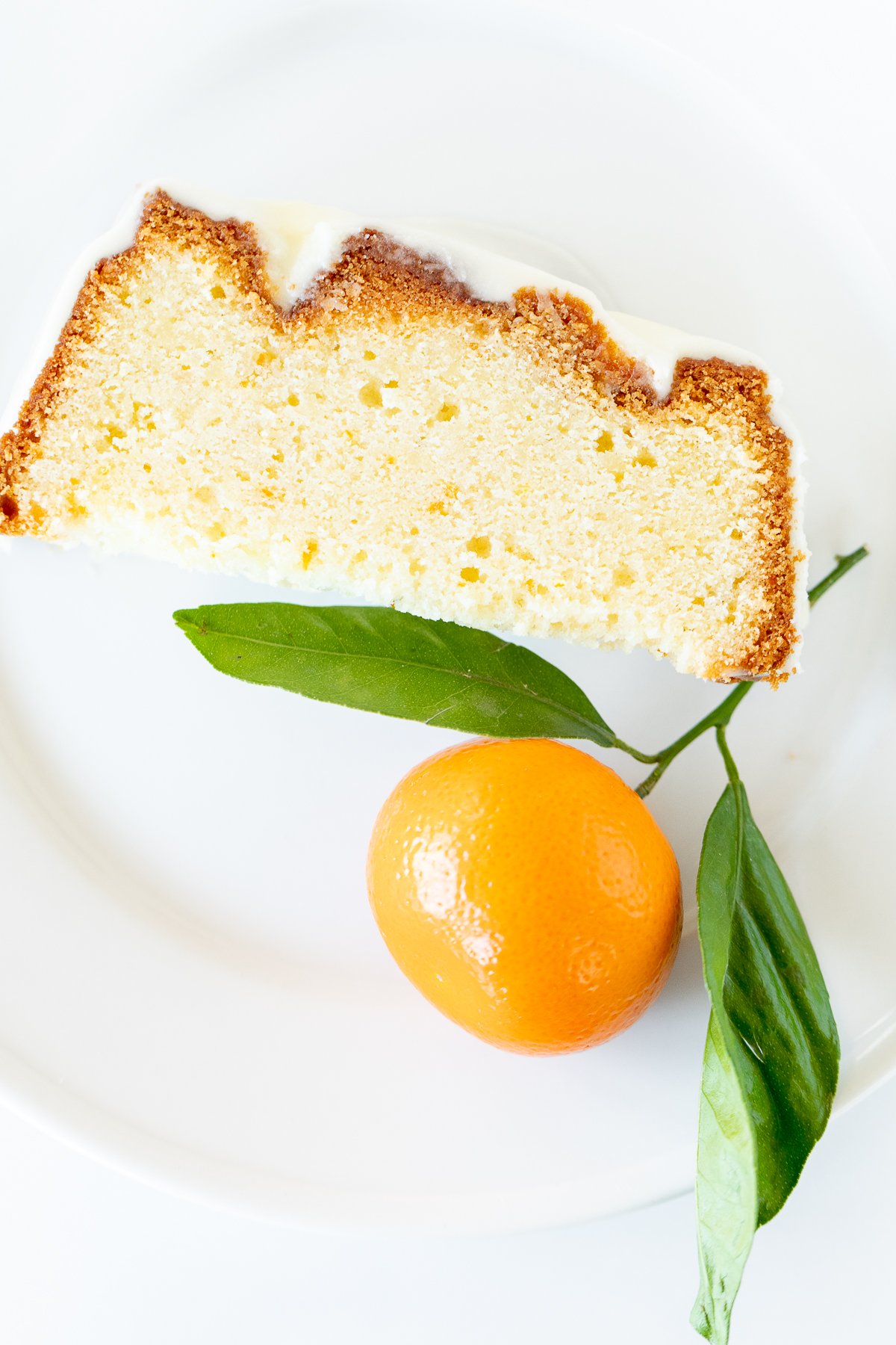 A slice of orange pound cake on a white plate.
