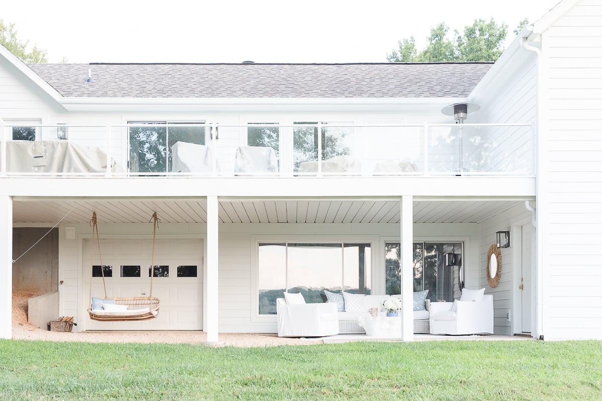 A white house with a swing on the porch featuring under deck waterproofing.