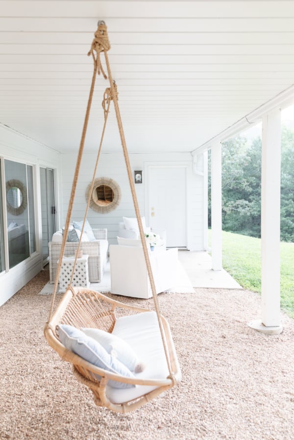 A white hammock hanging under a porch with an under deck ceiling.