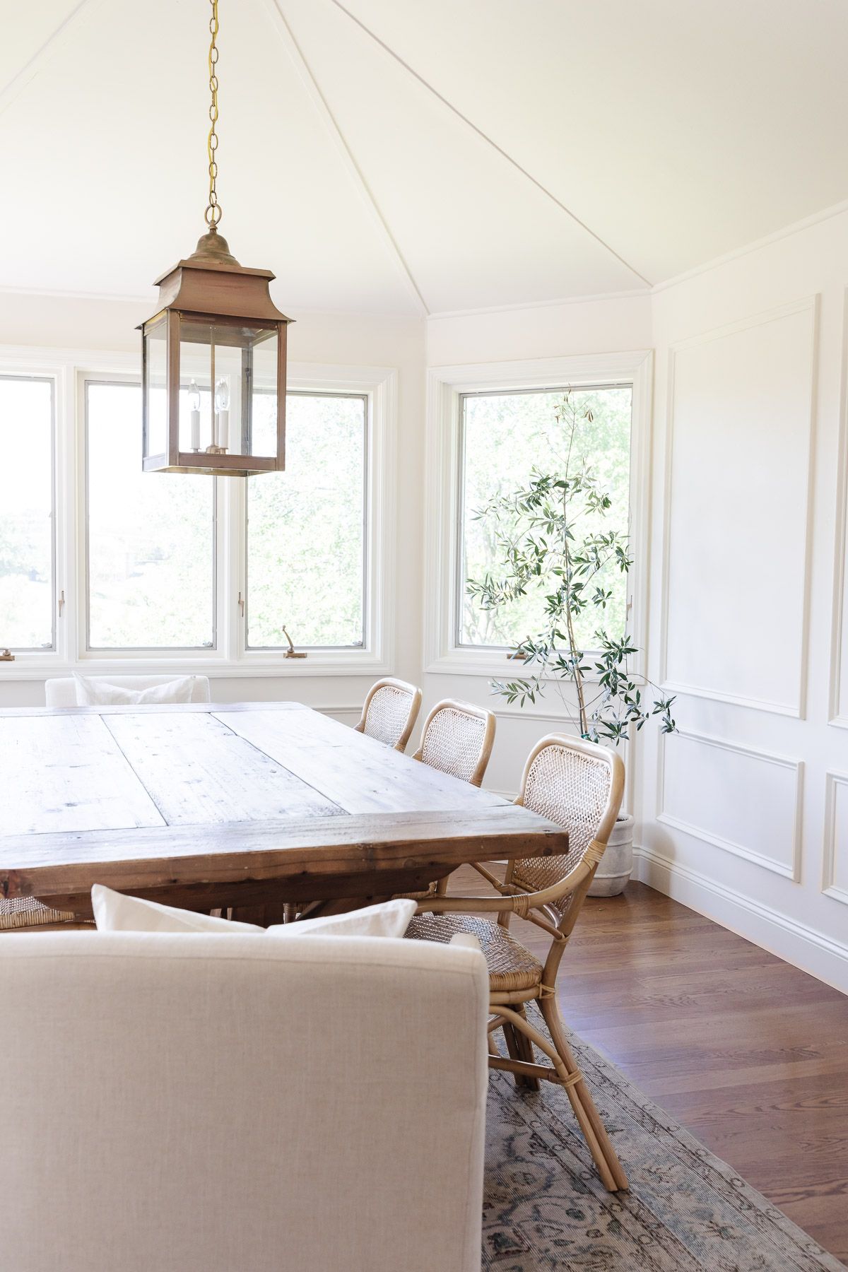 A dining room with a wood table, and walls and trim painted the same color white.