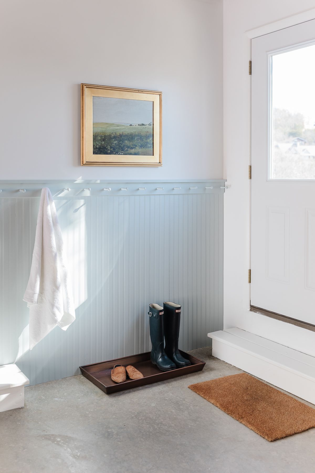 A mudroom area in a garage with blue painted beadboard and peg rail.