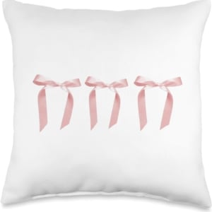 Three pink bows on a white pillow in a tween girl bedroom.