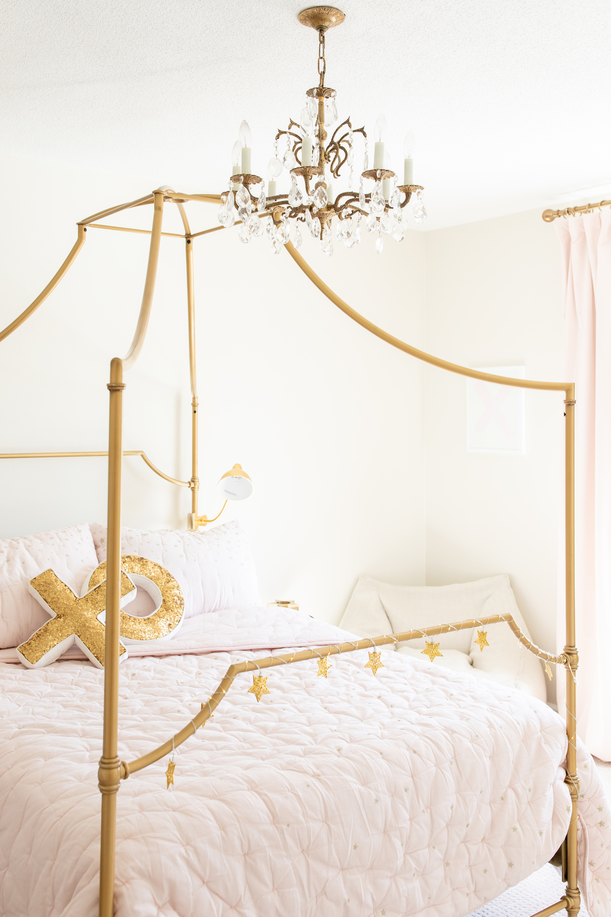 A cream, pink and gold tween bedroom with a gold canopy bed.