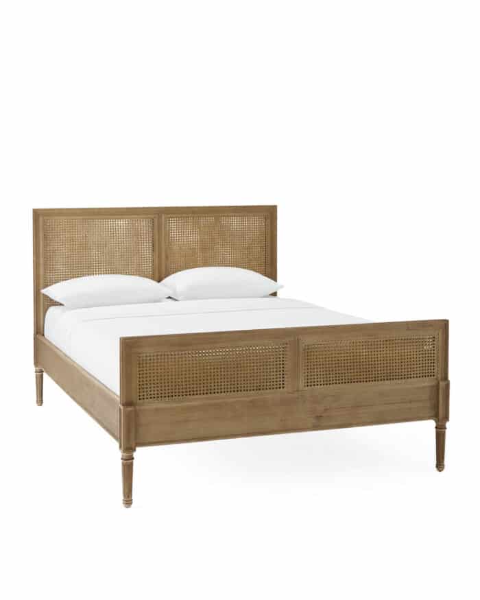 A rattan bed with white bedding and a white background for a product shot.
