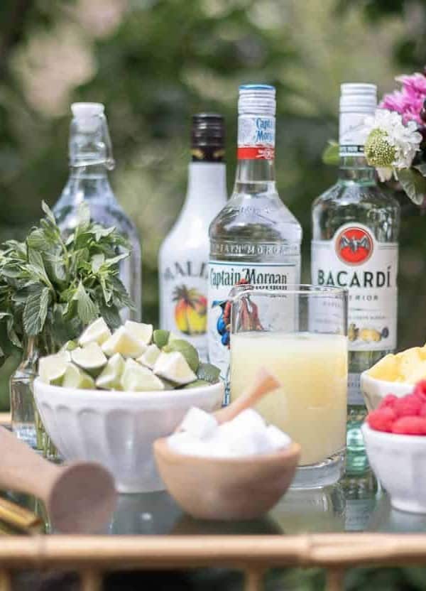 An at-home mojito bar cart with a variety of the best rums for mojitos in the background.