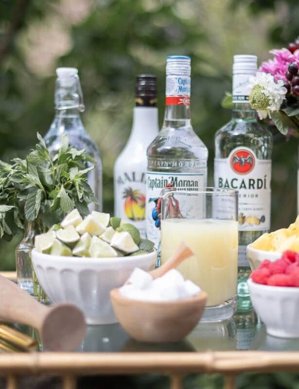 An at-home mojito bar cart with a variety of the best rums for mojitos in the background.