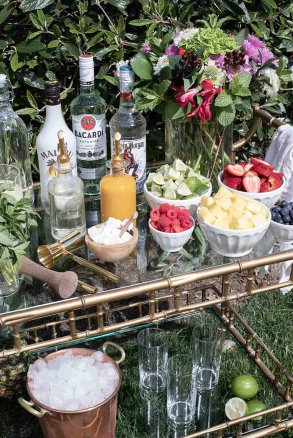 An at-home mojito bar cart with a variety of the best rums for mojitos in the background.