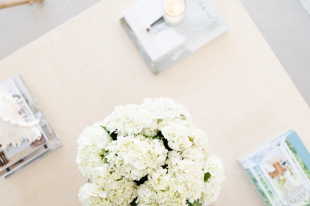 A raffia coffee table with flowers and books.