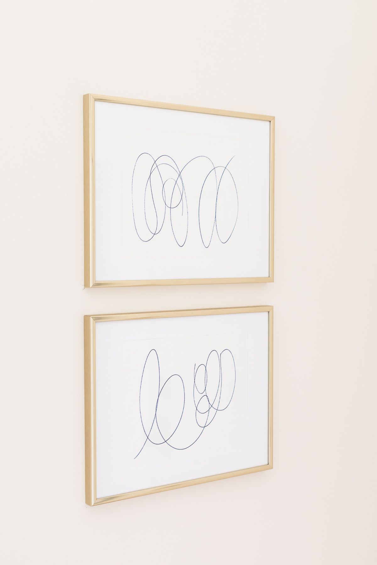 Coastal modern art with brass frames, two white pieces with blue circular scribbles