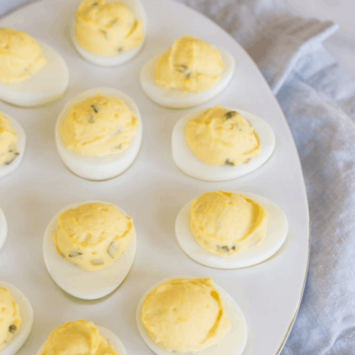 A white oval tray full of a make ahead appetizer for Christmas - deviled eggs!