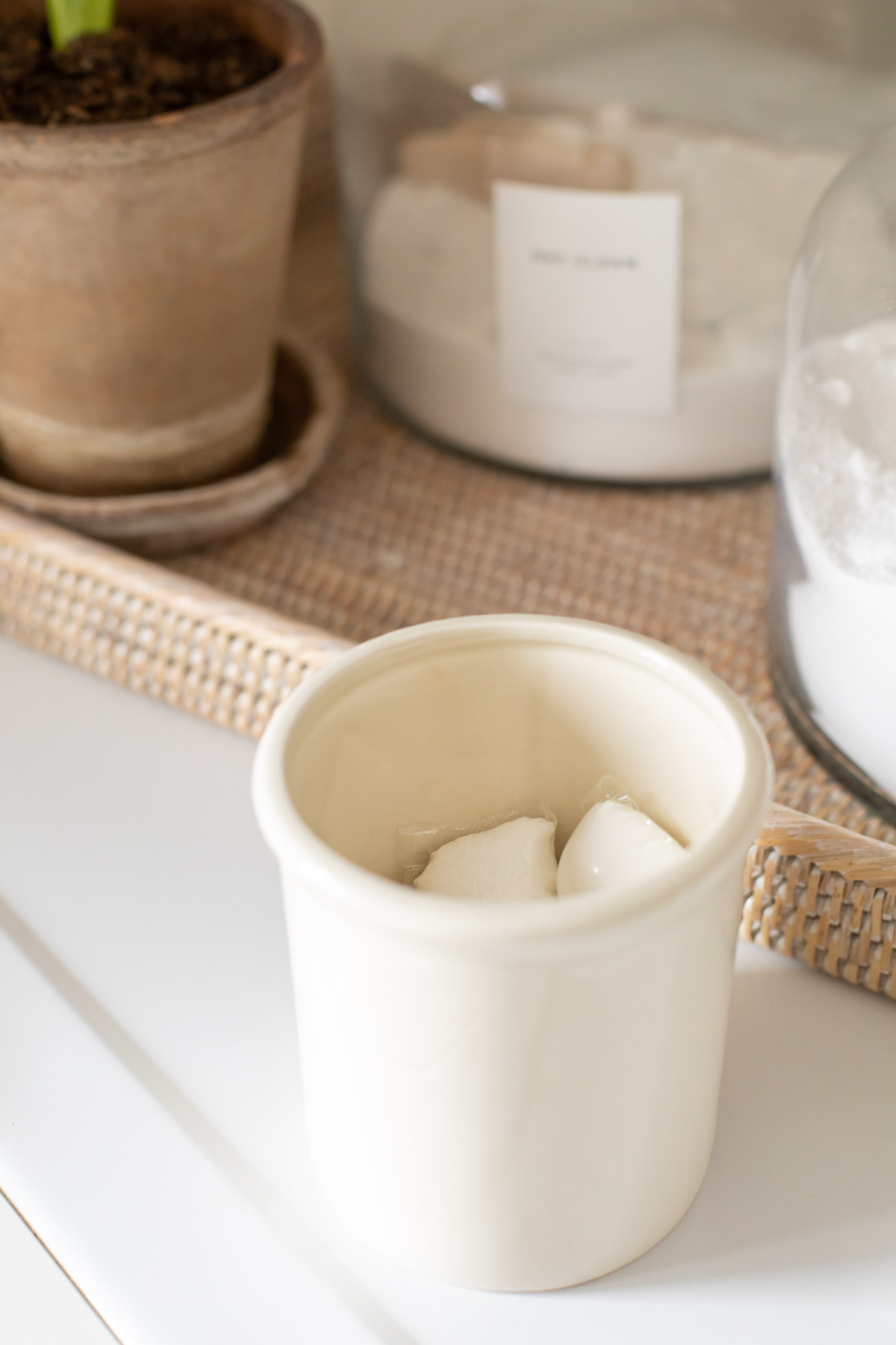 A white bowl of sugar next to a potted plant in a laundry room organized space.