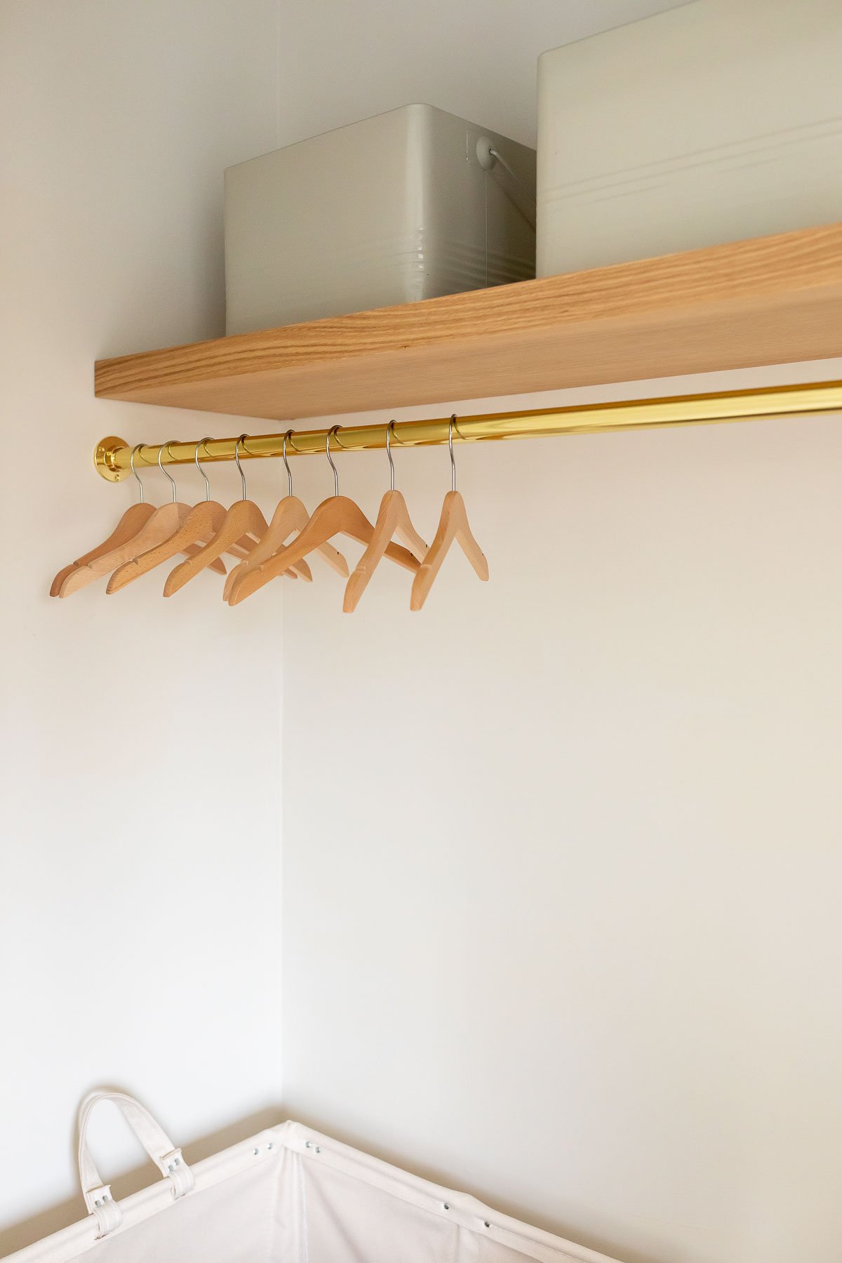 An organized laundry room with clothes hanging on a shelf.