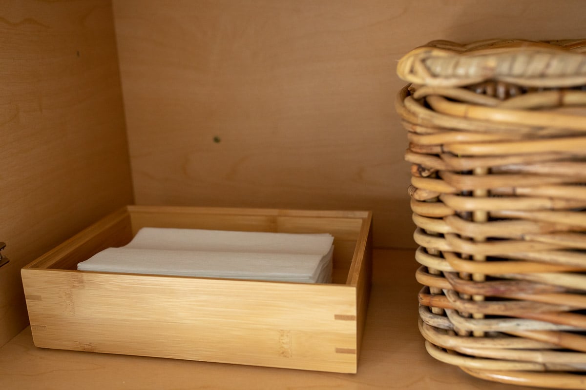 A wicker basket filled with towels and toilet paper, perfect for laundry room organization.