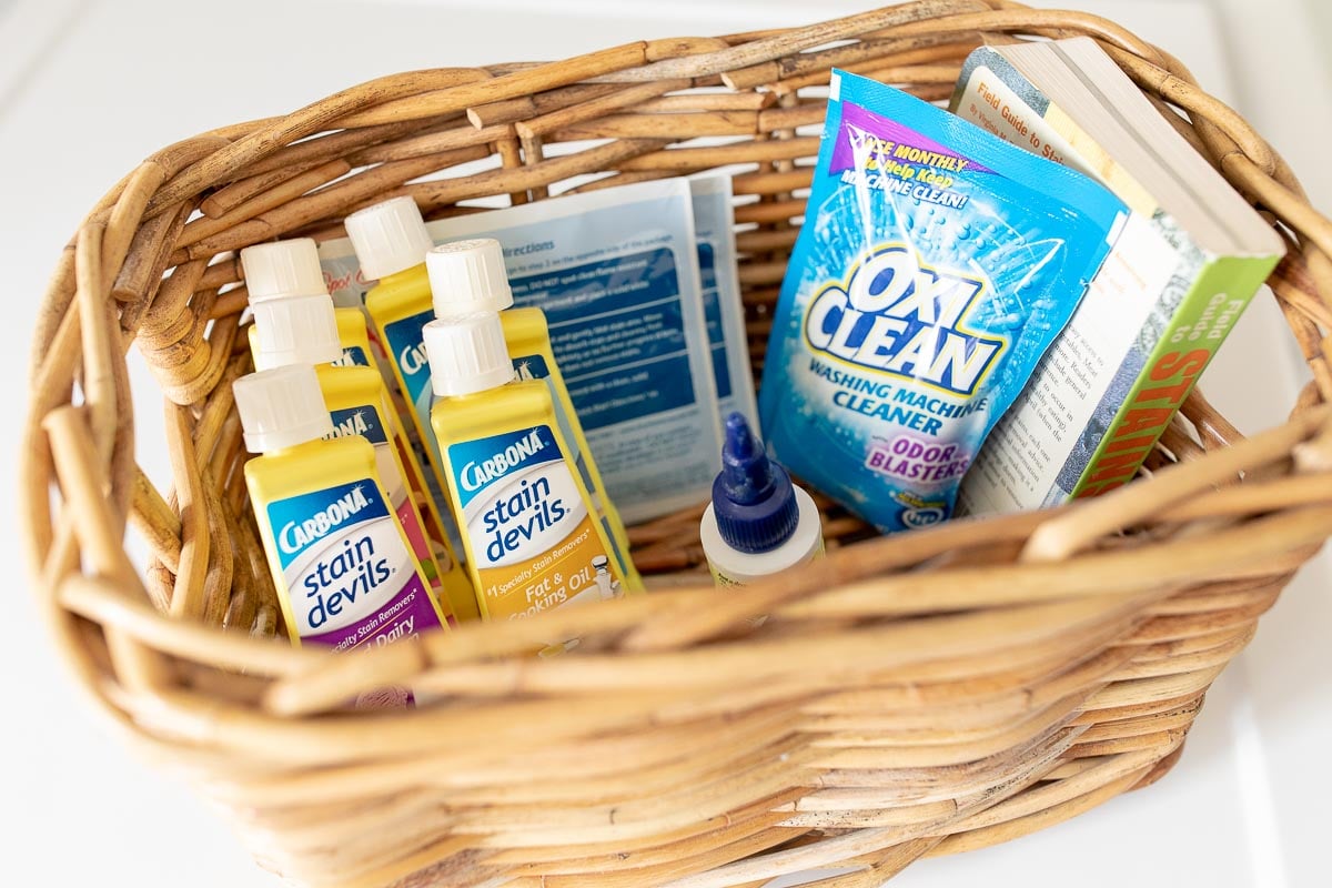 An organized wicker basket filled with cleaning supplies in a laundry room.