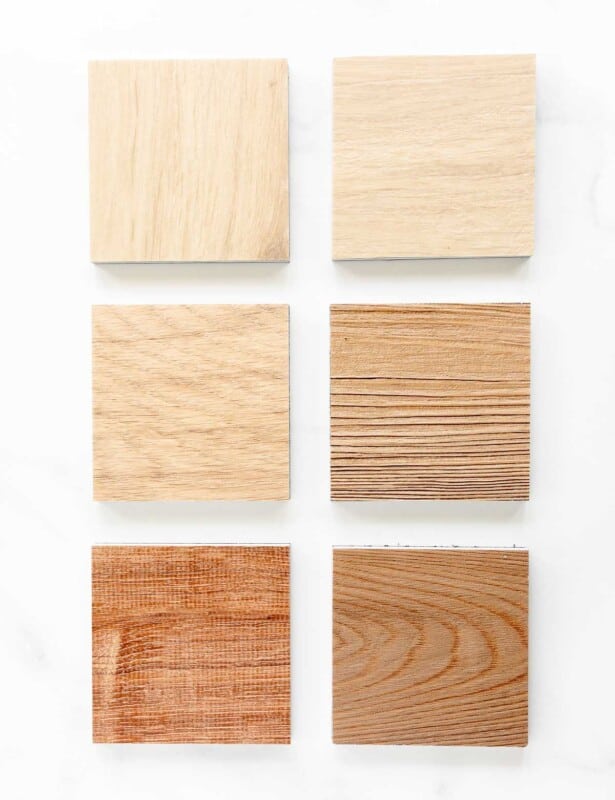 Six small samples of lvp flooring on a white surface.