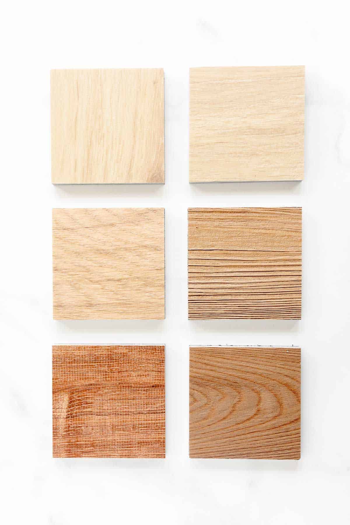 Six small samples of lvp flooring on a white surface.