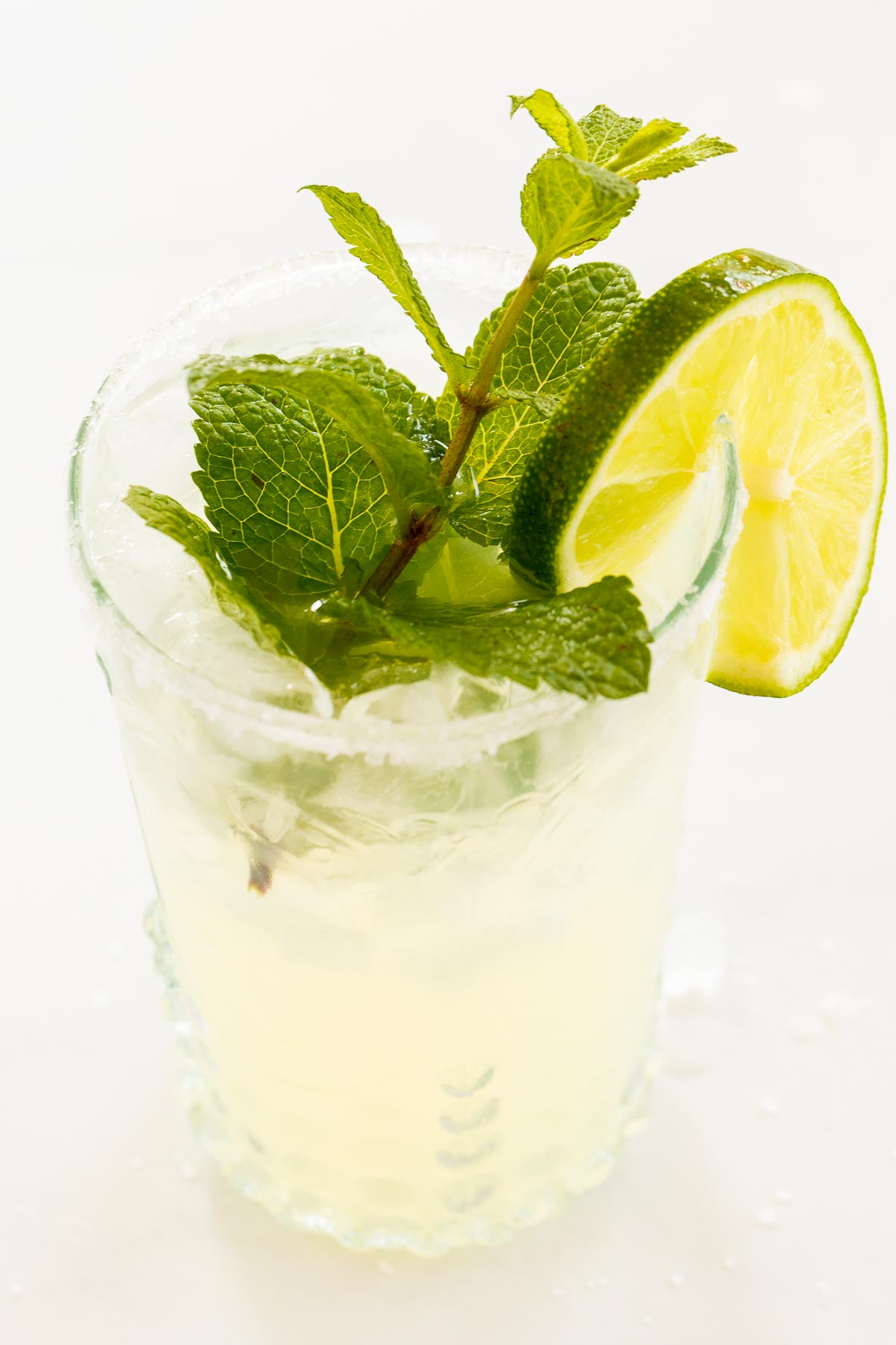 A mint margarita in a clear glass on a white surface